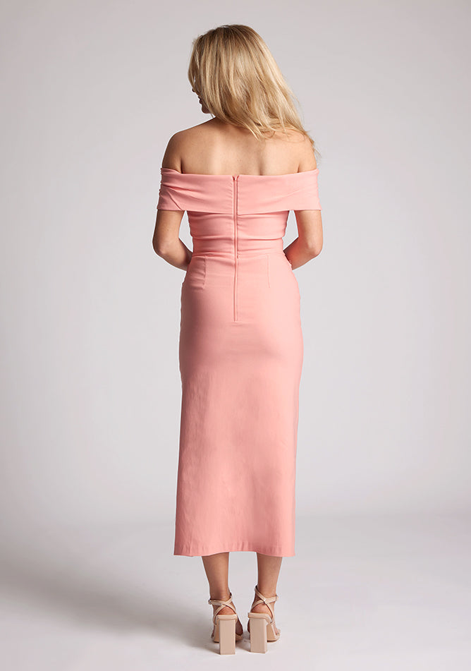Back image of a model wearing a Peach Midaxi Dress with an elegant off-shoulder neckline, a daring front skirt split, and a sleek bodycon design. Made with high-quality fabric, a design features Vesper Fraser Peach Midaxi Dress