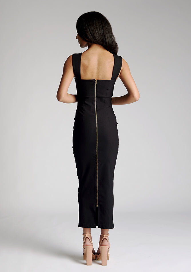 Back image of a model wearing a black midaxi dress, featuring a scoop neckline with wide straps and a gold statement zip at the centre back. The dress feature is the Vesper Edina Black Midaxi Dress