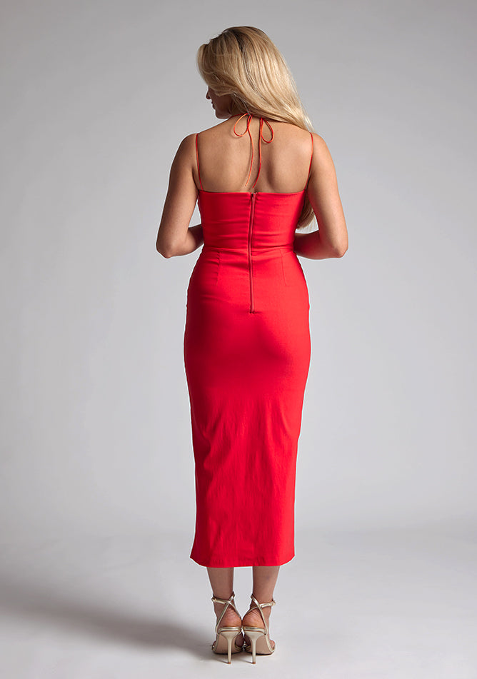 Back image of a blonde model wearing a red midaxi dress with a two alluring strappy designs, bodycon fit and a front skirt split. The design featured is the Vesper Alyssa Red Bodycon Midaxi Dress