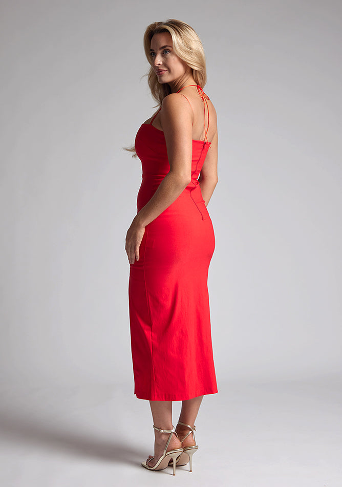 Back quarter image of a blonde model wearing a red midaxi dress with a two alluring strappy designs, bodycon fit and a front skirt split. The design featured is the Vesper Alyssa Red Bodycon Midaxi Dress