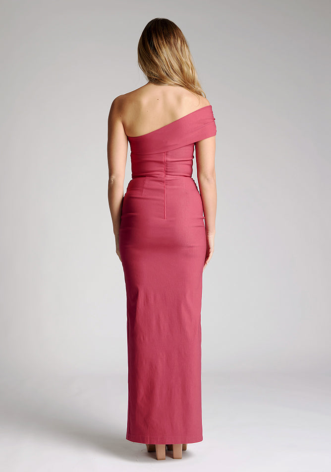 Back image of model wearing a raspberry maxi dress with a stunning one-sleeve off-shoulder design and an alluring front skirt split. The design featured is the Vesper Carmel Raspberry Maxi Dress