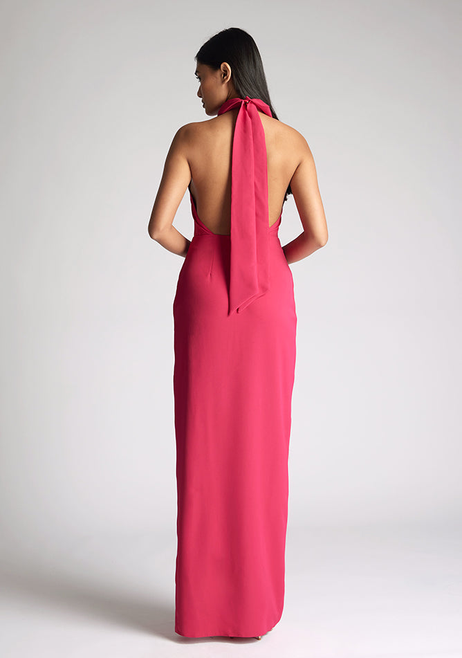 Back image of a model wearing a cerise maxi dress with a flattering halter neckline and with its eye-catching blue hue and a front skirt split. The design featured is the Vesper Davina Cerise Maxi Dress
