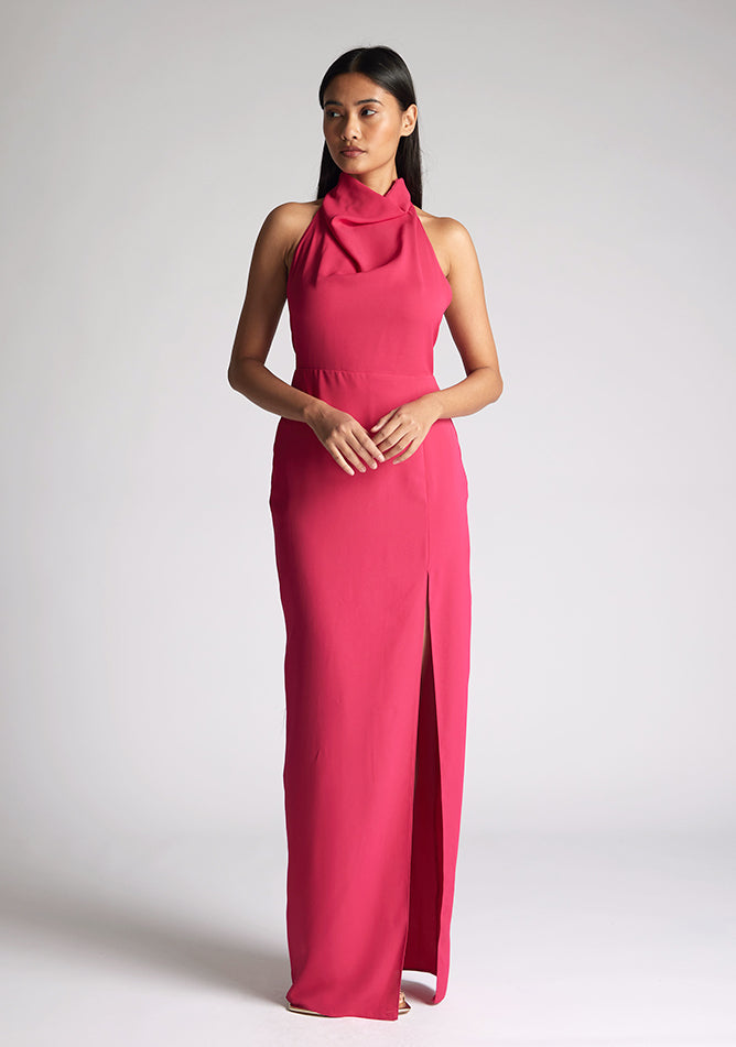 Front image of a model wearing a cerise maxi dress with a flattering halter neckline and with its eye-catching blue hue and a front skirt split. The design featured is the Vesper Davina Cerise Maxi Dress