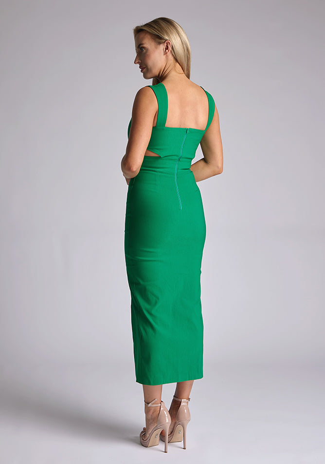 Back quarter image of a model wearing a green cut out midaxi dress with a sweetheart neckline with wide straps, a side cut-out and front skirt split. The design featured is the Vesper Porticini Emerald Green Cut Out Midaxi Dress