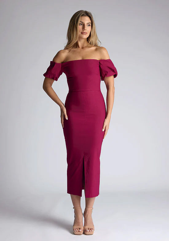 Front image of a blonde model wearing a berry midaxi dress with a bardot neckline gracefully frames the shoulders, while the back zip ensures a seamless silhouette. The dress features is the Vesper Quinton Berry Midaxi Dress