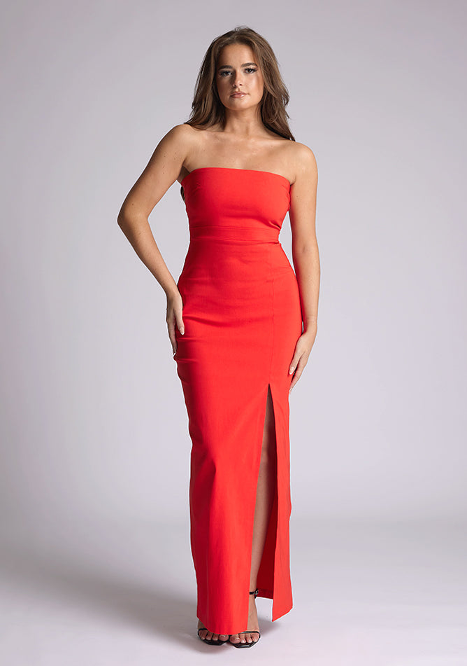 Front image of the model wearing a red bodycon maxi dress, with a strapless neckline and a front split. The design featured is the Vesper Salma Red Midaxi Dress.