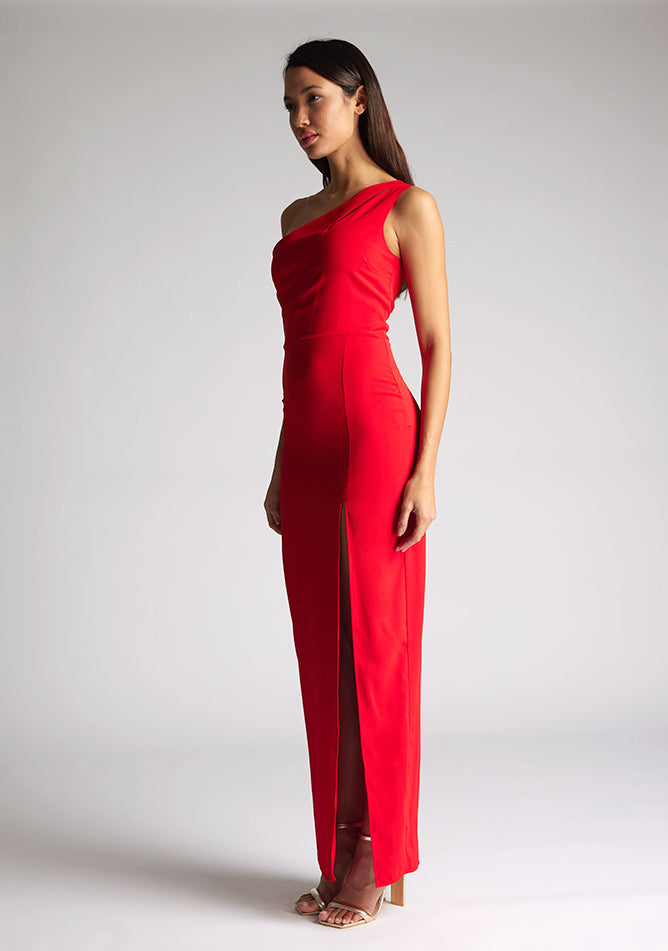 Front quarter image of model wearing red asymmetric maxi dress with a asymmetric neckline with one shoulder detail, front bodice cut-out and front skirt split. The design featured is Vesper Verity Red Asymmetric Maxi Dress