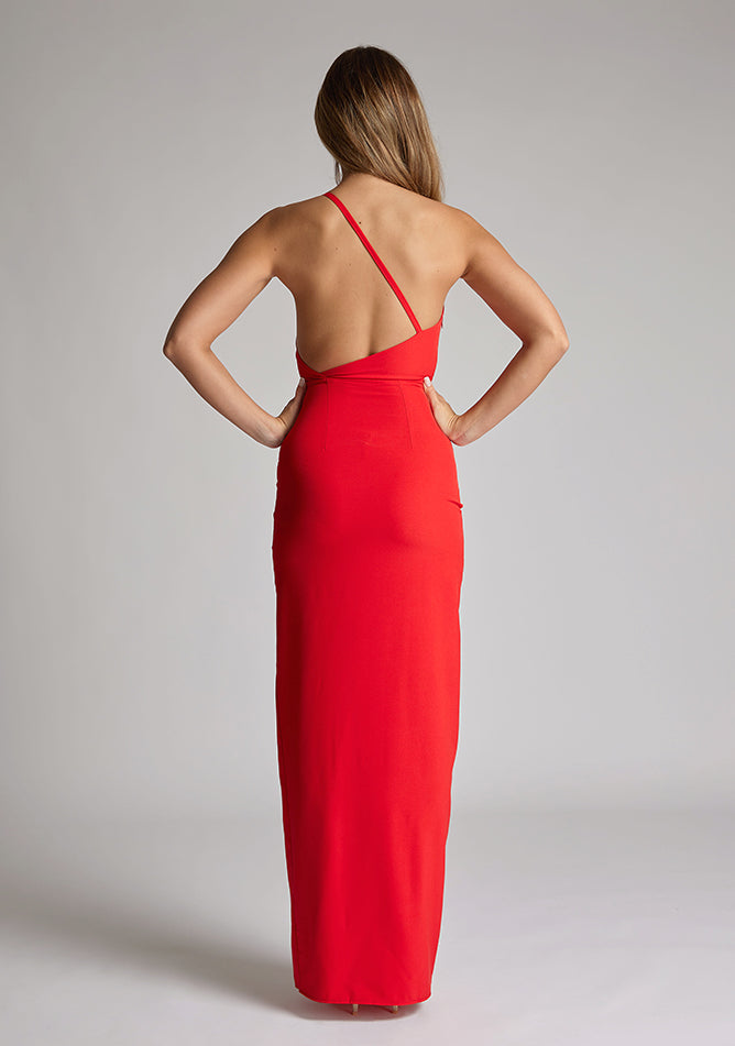 Back image of a model wearing a red maxi dress with a asymmetric neckline, one shoulder strap, front skirt split and open back with asymmetric strap across back. The design featured is Vesper Viva Red Maxi Dres