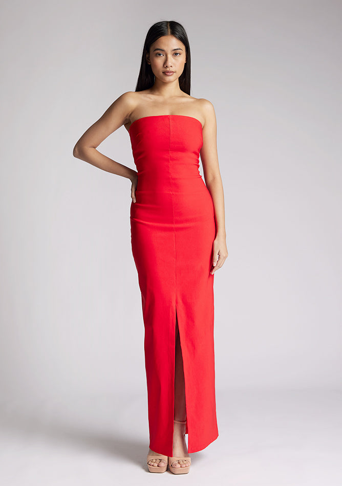 Front image of a model wearing a red strapless maxi dress with a front split and centre back zip. The design featured is the Vesper Alaya strapless maxi dress