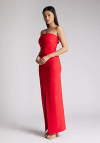 Front quarter image of a model wearing a red strapless maxi dress with a front split and centre back zip. The design featured is the Vesper Alaya strapless maxi dress
