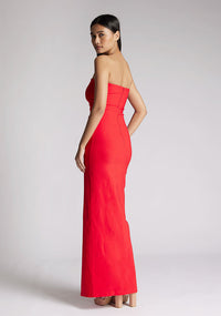  Back quarter image of a model wearing a red strapless maxi dress with a front split and centre back zip. The design featured is the Vesper Alaya strapless maxi dress