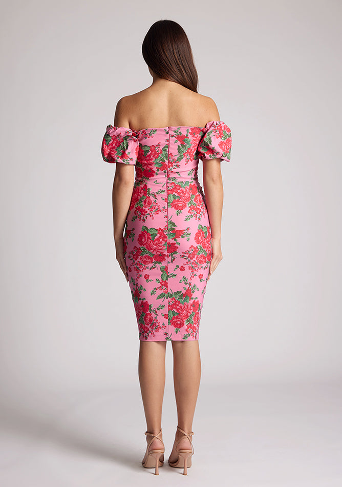 Back image of a model wearing a floral bardot dress, featuring puff sleeves and a midi length. The dress featured is the Anastasia Pink Floral Bardot Midi Dress
