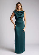 Front image of a model wearing a pine satin cowl neck dress, the dress is maxi length and features back detailing with the straps. The dress featured is the Anoushka pine maxi dress