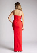 Back image of a model wearing a red square neck maxi dress, featuring delicate straps and waist detailing. The dress featured is the Vesper Bergen maxi dress