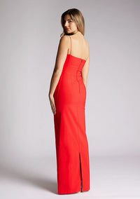 Back quarter image of a model wearing a red square neck maxi dress, featuring delicate straps and waist detailing. The dress featured is the Vesper Bergen maxi dress