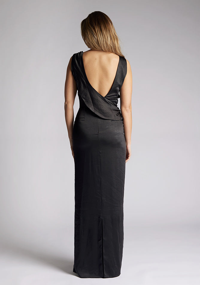 Back image of a model wearing a black satin maxi dress, featuring a cowl neck ruched detail and an open back. The dress featured is the Vesper Bertie black maxi dress