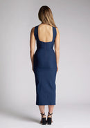 Back image of a model wearing a navy cut out midaxi dress. The dress features a key hole cut out at the front and a back less design. The dress featured is the Vesper Carter navy midaxi dress