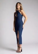 Front quarter image of a model wearing a navy cut out midaxi dress. The dress features a key hole cut out at the front and a back less design. The dress featured is the Vesper Carter navy midaxi dress