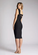 Back quarter image of a model wearing a black midi dress, featuring a body con design and an assymetric double strap design. The dress featured is the Vesper Denver black midi dress