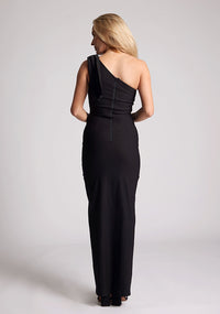 Back image of a model wearing a black one shoulder maxi dress with bow detailing at the shoulder. The dress featured is the Eimer black maxi dress