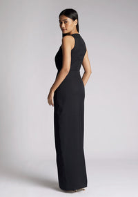 Back quarter image of a model wearing a black sleeveless maxi dress, featuring a front split and a v neck design. The dress featured is the Vesper Elba black maxi dress