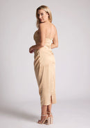Back quarter image of a model wearing a champagne satin midaxi dress featuring a halter neck and a ruched design. The dress featured is the Vesper Electra champagne satin midaxi dress