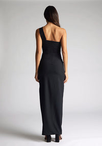 Back image of the model wearing a Black Maxi Dress with a one-shoulder design with a front cut-out, and a front skirt split, a design features Vesper Ellis Black Maxi Dress