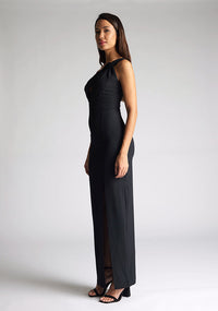 Front quarter image of the model wearing a Black Maxi Dress with a one-shoulder design with a front cut-out, and a front skirt split, a design features Vesper Ellis Black Maxi Dress