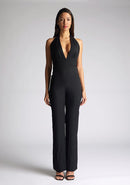 Front image of the model wearing a Black Jumpsuit with a plunge neckline, and a open back detail, a design features Vesper Flynn Black Jumpsuit