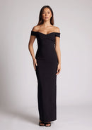Front image of a model wearing a black maxi dress, featuring off the shoulder short sleeves and a dipped back design. The dress featured is the Vesper Holland black maxi dress