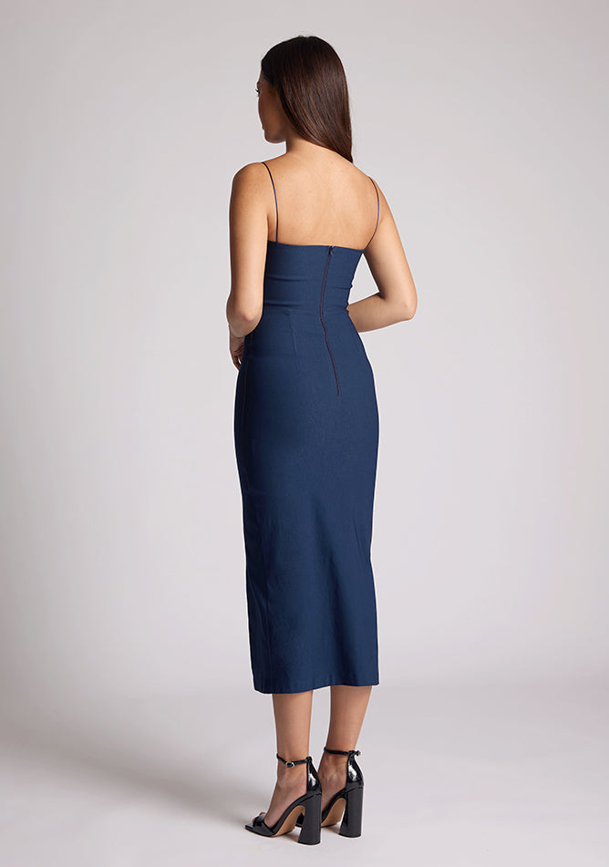 Back quarter image of a model wearing a navy dress with two cut out sections at the bust. The dress featured is the Kendall navy midaxi dress