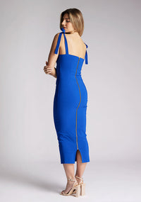 Back quarter image of a model wearing a cobalt blue midaxi dress. The dress features a V cut out in the neck line and tie up straps. The dress featured is the Vesper Letty cobalt midaxi dress