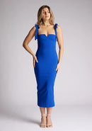 Front image of a model wearing a cobalt blue midaxi dress. The dress features a V cut out in the neck line and tie up straps. The dress featured is the Vesper Letty cobalt midaxi dress