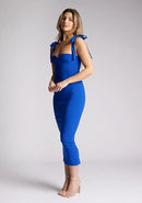 Front quarter image of a model wearing a cobalt blue midaxi dress. The dress features a V cut out in the neck line and tie up straps. The dress featured is the Vesper Letty cobalt midaxi dress