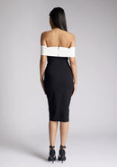 Back image of a model wearing a off the shoulder midi dress, featuring a black body to the dress with a white band across the top and the arms. The dress featured is the Vesper Maricel monochrome midi dress