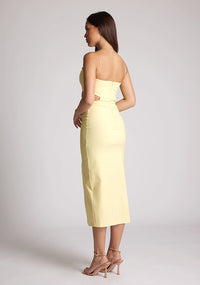 Back quarter image of a model wearing a sherbert midi dress, featuring cut outs at the waist and a front split in the skirt. The dress featured is the Vesper Marilynn sherbert midaxi dress