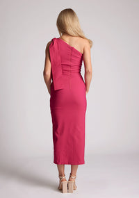 Back image of a model wearing a cerise midaxi dress, featuring a one shoulder design and a front side split. The dress featured is the Vesper Odette cerise midaxi dress