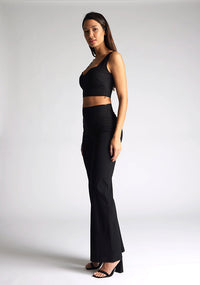 Front quarter image of a model wearing a black crop top, featuring a sweetheart neckline and thick straps. The top featured is the Vesper Sky black crop top worn with Vesper June black wide leg trousers