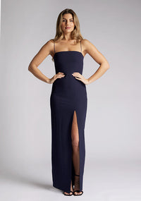 Front image of a model wearing a navy maxi dress, featuring delicate straps and a front skirt split. The dress featured is the Vesper Tate navy maxi dress
