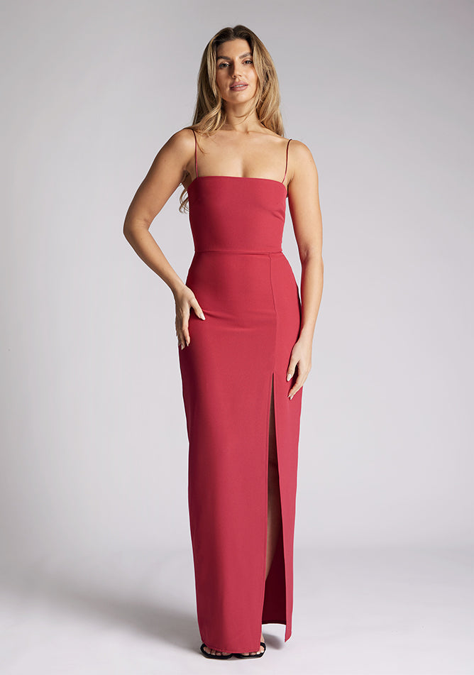 Front image of a model wearing a raspberry maxi dress, featuring delicate straps and a front skirt split. The dress featured is the Vesper Tate raspberry maxi dress