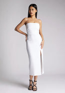 Front image of a model wearing a white midaxi dress, featuring delicate straps and a front skirt split. The dress featured is the Vesper Tate white midaxi dress