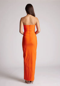 Back image of a model wearing an orange strapless maxi dress with a front split and centre back zip. The design featured is the Vesper Alaya Orange Bodycon Maxi Dress.