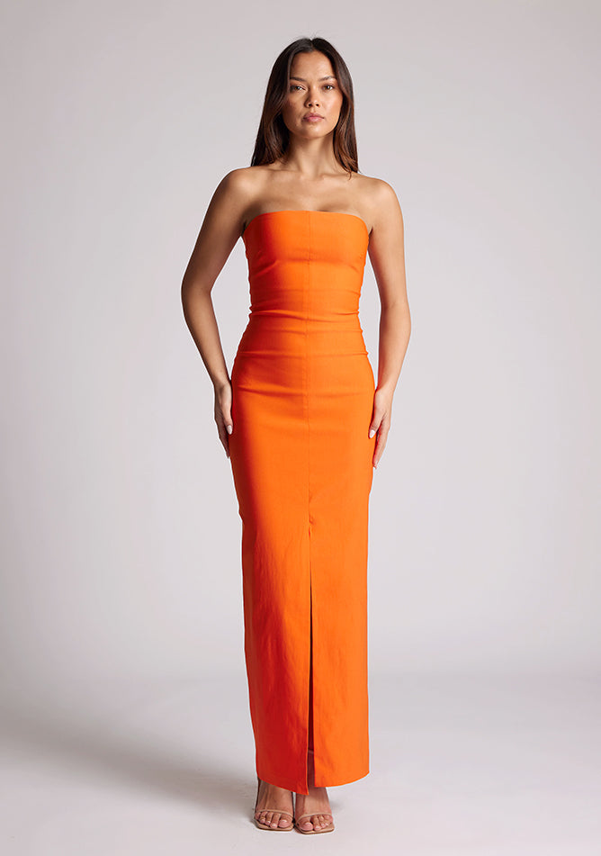 Front image of a model wearing an orange strapless maxi dress with a front split and centre back zip. The design featured is the Vesper Alaya Orange Bodycon Maxi Dress