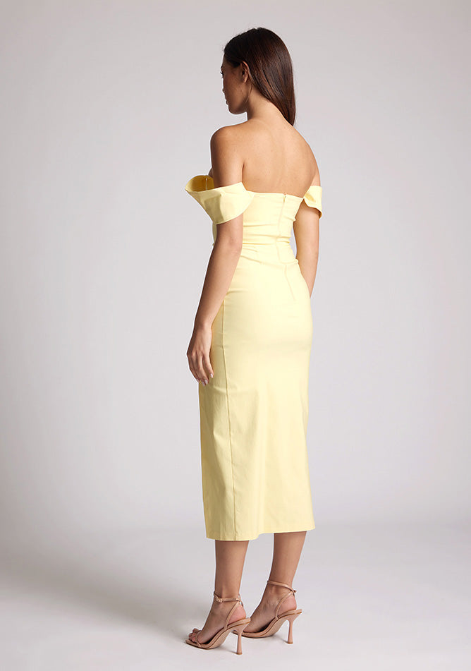 Back quarter image of a model wearing a yellow bardot midaxi dress with a stunning bardot neckline with armbands and a front skirt split. The design featured is the Vesper Astra Yellow Bardot Midaxi Dress