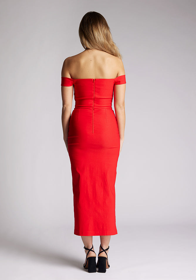 Back image of a model wearing a red midaxi dress, featuring a bardot neckline with subtle sweetheart detail, off shoulder style bands and a front skirt split. The style featured is Vesper Clara Red Midaxi Dress.