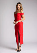 Quarter front image of a model wearing a red midaxi dress, featuring a bardot neckline with subtle sweetheart detail, off shoulder style bands and a front skirt split. The style featured is Vesper Clara Red Midaxi Dress.