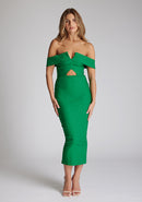 Front image of a model wearing a emerald green midaxi dress with a off-shoulder bardot neckline, with arm bands v-shaped cut-out at neckline and keyhole cut-out under bust and bodycon style dress with a statement gold zip at centre back. The design featured is the Vesper Daphne Emerald Green Midaxi Dress