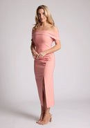Front quarter image of a model wearing a Peach Midaxi Dress with an elegant off-shoulder neckline, a daring front skirt split, and a sleek bodycon design. Made with high-quality fabric, a design features Vesper Fraser Peach Midaxi Dress