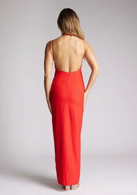 Back image of a model wearing a red halter neck maxi dress, featuring a keyhole cut out and a front skirt split. The dress featured is the Vesper Ivie red maxi dress