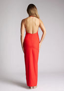 Back image of a model wearing a red strappy maxi dress with a halter neckline with a chic back fastening and subtle keyhole detail, its backless design exudes refinement and front skirt split. The design featured is the Vesper Ivie Red Strappy Maxi Dress